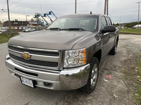 A 2013 Chevrolet Silverado Hybrid with a metallic gray exterior and a chrome grille parked on the roadside