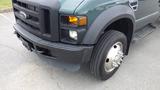 2008 Ford F-450 SD with a green exterior showing the front grille headlights and a large front tire