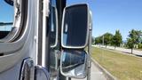 A 2006 Ford Econoline with large side mirrors reflecting light from a bright day