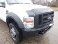 A white 2009 Ford F-450 SD pickup truck with a black grill and large tires, showcasing its front view and distinctive design features