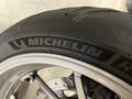 Close-up of a motorcycle tire with Michelin branding mounted on a silver alloy wheel