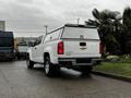 A white 2019 Chevrolet Colorado pickup truck with a truck bed cover parked on a paved surface