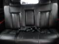 A black leather seat from a 2008 Cadillac Limousine featuring multiple seatbelts and a plush, cushioned design