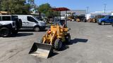 A yellow 2024 Traner TR45 compact loader with a front bucket and a black seat under a red canopy parked on a gravel surface