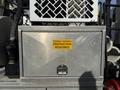 A metallic storage compartment on a 2013 International 7400 truck with a bright yellow sign that reads DOUBLE HEARING PROTECTION REQUIRED