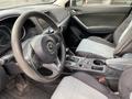 Interior of a 2016 Mazda CX-5 showing the steering wheel dashboard and front seats with a modern design and light gray upholstery