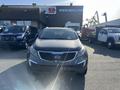 A 2012 Kia Sportage with a dark gray exterior is parked in a dealership lot flanked by other vehicles