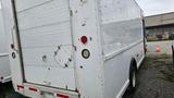 A white 2006 Ford Econoline cargo van with a rear door and red tail lights parked on a gravel surface