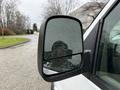 A side mirror of a 2009 Chevrolet Express with raindrops on the glass and a reflection visible in the mirror