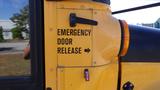 A yellow school bus featuring a door with text that reads Emergency Door Release and an arrow pointing to the right