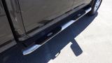 A metallic side step attached to a 2014 RAM 3500 truck with textured rubber inserts for grip