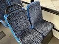 Two blue and patterned fabric seats inside a passenger section of a bus