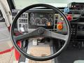 View of the steering wheel and dashboard of a 2001 Freightliner FL80 with various gauges and control buttons