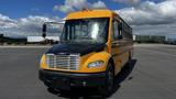 A 2014 Freightliner Thomas bus in yellow and black with large windows and a front grille featuring horizontal slats