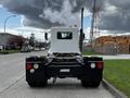 A 2014 Kenworth T370 truck viewed from the rear with a white cabin and black chassis featuring large taillights and a visible exhaust pipe