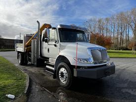 A white 2013 International DuraStar 4300 truck with a yellow dump bed and a front-mounted plow attachment