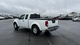 A white 2016 Nissan Frontier pickup truck parked with its bed facing the viewer and a cab with two doors