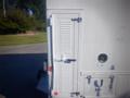 A 2006 Freightliner FS65 with a white exterior featuring a metal rear door and a circular access port on the side