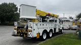 A 2006 International 7500 utility truck with a white body and a yellow crane mounted on the rear used for aerial work