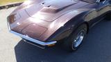 A classic 1971 Chevrolet Corvette Stingray in a deep maroon color with a distinctive hood and chrome detailing on the front and large tires with white lettering