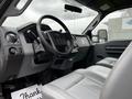 Interior of a 2011 Ford F-250 SD featuring a steering wheel and gray leather seats with various controls and dashboard instruments visible