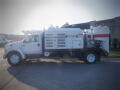 A 2007 Ford F-650 vacuum truck with a large tank and hose attachment on the side is displayed in profile view