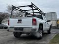 A white 2018 GMC Sierra 1500 truck with a black rack mounted in the bed and exhaust smoke visible from the rear