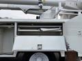 A white 2007 International 4200 bucket truck with an open storage compartment showing a folded ladder inside
