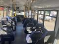 Interior view of a 2018 Chevrolet Express featuring rows of blue seats with a driver's area at the front and no passengers onboard