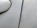 Close-up view of a white 2016 Mazda CX-5 door with visible scratches and water droplets on its surface