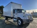 A 2013 International 4300 box truck with a silver and white exterior parked at an angle showing the driver's side and front view