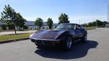 A 1971 Chevrolet Corvette Stingray in a dark color with a sleek body design and prominent front grille showcasing its classic styling and sporty features