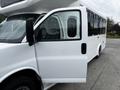 A white 2017 Chevrolet Express van with an open driver's side door showcasing the interior design and seating arrangement