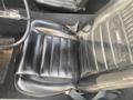 Black leather seat of a 1966 Ford Mustang featuring horizontal stitching and a stitched pony emblem at the top