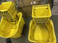 Ten yellow mop buckets and assorted brooms arranged together