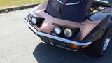 A maroon 1971 Chevrolet Corvette Stingray with distinctive headlights and a sleek hood design