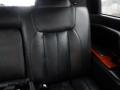 Interior of a 2008 Cadillac Limousine featuring a black leather seat with vertical stitching and a wooden armrest