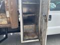 A 2010 Ford F-550 with an open compartment revealing metal shelving and a clean interior space designed for storage