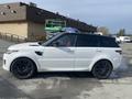 A 2020 Land Rover Range Rover Sport in white with black wheels parked at a commercial location