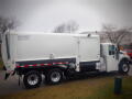 A white 2008 International 7400 garbage truck with a rear-loading mechanism and large wheels parked on a street