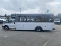 A 2017 Chevrolet Express bus with a white exterior and large windows parked in a lot