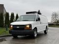 A white 2009 Chevrolet Express van with a black roof-mounted unit parked on a street