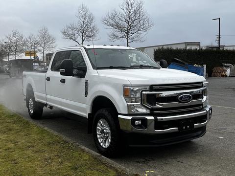 A white 2020 Ford F-350 Super Duty pickup truck is parked with a chrome front grille and large wheels