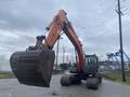 A 2006 Hitachi ZX200LC excavator with a large bucket attachment positioned in front of the cab and tracks raised above the ground