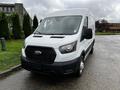 A white 2021 Ford Transit van with a black grille and headlights facing forward parked on a wet surface