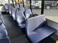 Interior seating of a 2018 Chevrolet Express showing several dark blue fabric benches arranged in a row with sturdy backs and armrests