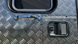 Close-up of a 1995 Freightliner FLL086 door handle and lock with a shiny diamond plate texture surrounding the area