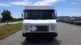 A white 2011 Ford Econoline van with a flat front and a blank license plate area standing on a paved surface