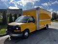 A yellow 2017 GMC Savana box truck with a large cargo area and a black front grille parked on a paved surface