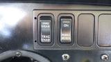 Close-up of three switches on a dashboard labeled DISAB TRAC ENAB ON PARKD REGEN